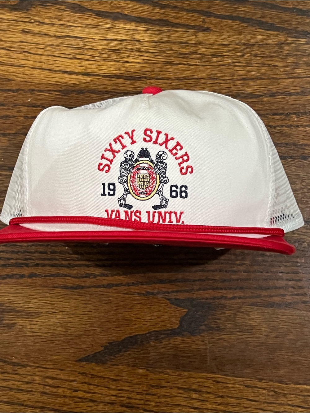 Vans Sixty Sixers trucker hat featuring a red crest graphic on the front.